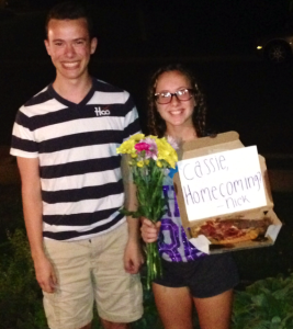   Freshman Cassie Diegtel stands with her homecoming date and a cheese pizza. Freshman Nick Carr asked her by delivering her favorite food to her house with a surprise twist.