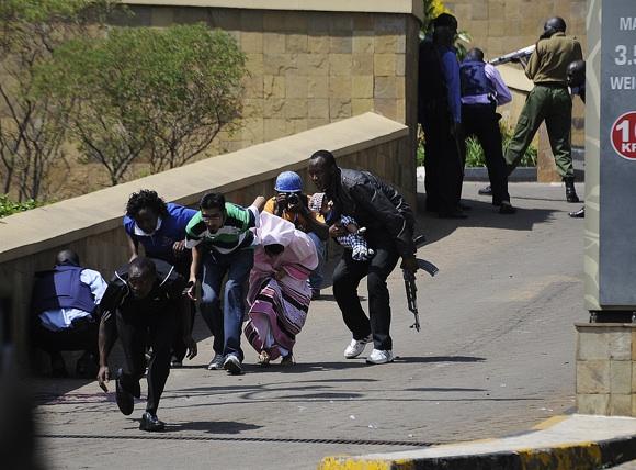 Policemen carry a baby to safety after masked gunmen stormed an upmarket mall and sprayed gunfire, killing at least six.The Gunmen are said to have taken up to seven hostages during the attack at Nairobis Westgate Mall.