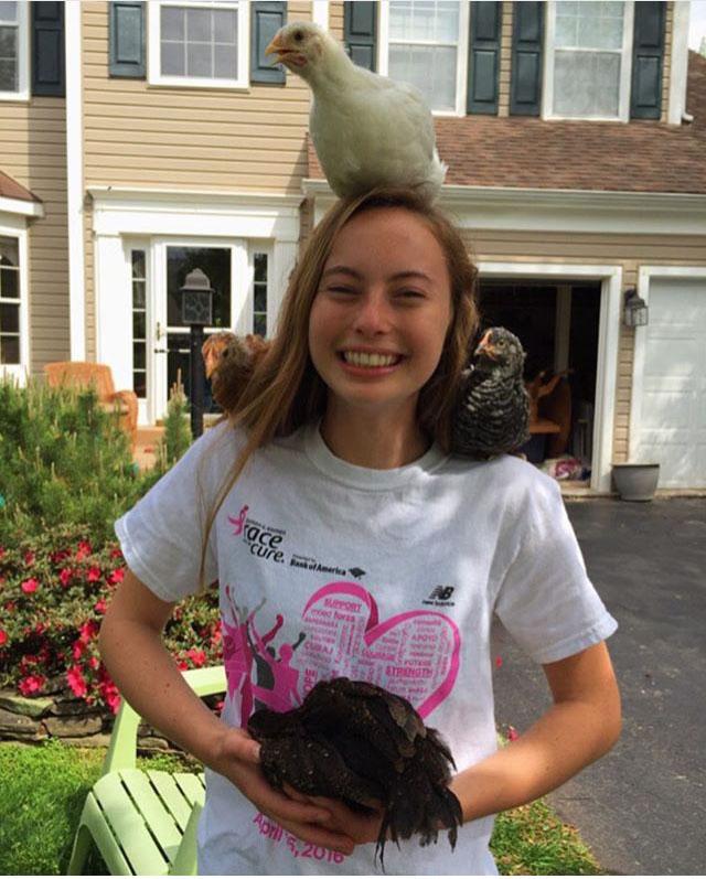 Brittany Schlosberg showing her love for animals while holding four chickens. Proudly smiling at the camera. 