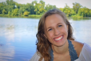Roberts poses by a lake, her bright smile reflecting her personality. She hopes to make the school more united through involvement.