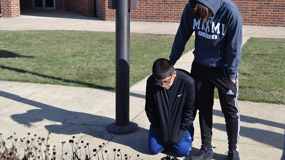 Junior Bryan Clavijo-Aranibar comforts freshman Omar Ayazi by the flagpole on March 14